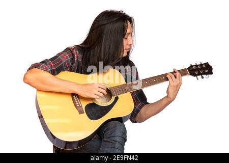 Portrait handsome young male guitarist with long hair sitting and playing acoustic guitar. Asian long-haired man playing acoustic guitar isolated on w Stock Photo