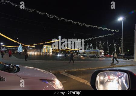 CHISINAU, MOLDOVA - DECEMBER 11, 2017: Great National Assembly Square at Christmas night with people walking and cars riding on road. Triumphal arch o Stock Photo