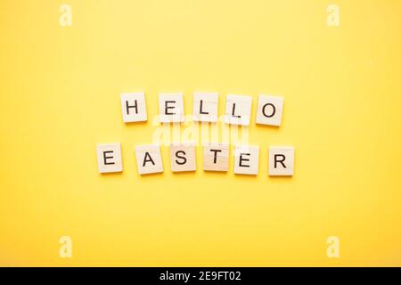 Phrase hello easter made from wooden blocks on a light yellow background Stock Photo