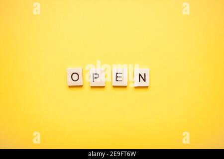 Phrase open made from wooden blocks on a light yellow background Stock Photo