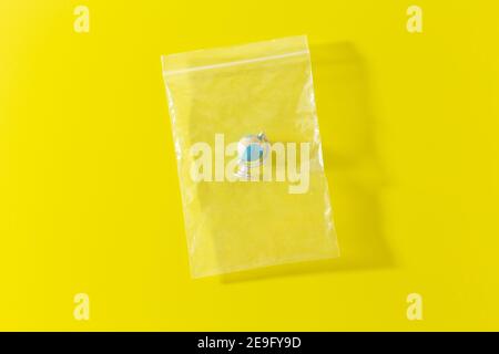 little planet Earth in polyethylene plastic disposable bag on yellow Stock Photo