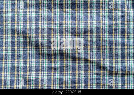 Plaid textile pattern of a blue green yellow garment. Fabric structure closeup of a vintage fashion clothing piece with wrinkles Stock Photo