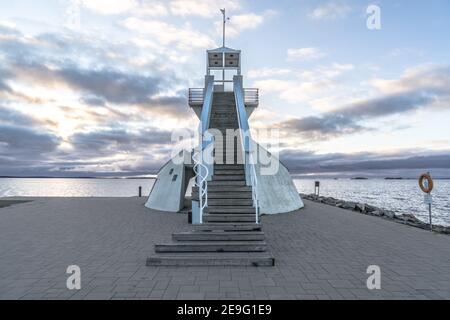 Symmetric lighthouse in Nallikari, Oulu, Finland. Scenic evening skyline over Baltic sea with clouds. Beautiful stairs to observation tower at the end Stock Photo