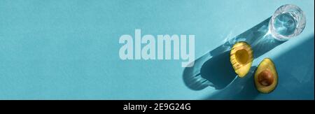 Oblong banner of two avocado halves isolated on turquoise coloured background with copy space Stock Photo