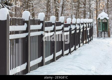 An iron fence, covered with snow in winter, against the background of an old telephone booth. Finnish nature and architecture. Seurasaari, Helsink. High quality photo Stock Photo
