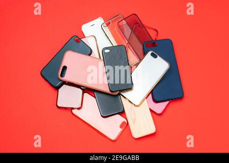 Pile of multicolored plastic back covers for mobile phones on red background Stock Photo