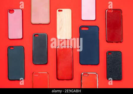 Pile of multicolored plastic back covers for mobile phone. Choice of smart phone protector accessories on red background. A lot of silicone phone back Stock Photo