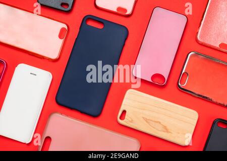 Pile of multicolored plastic back covers for mobile phone. Choice of smart phone protector accessories on red background. A lot of silicone phone back Stock Photo