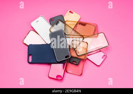 Pile of multicolored plastic back covers for mobile phones on pink background Stock Photo