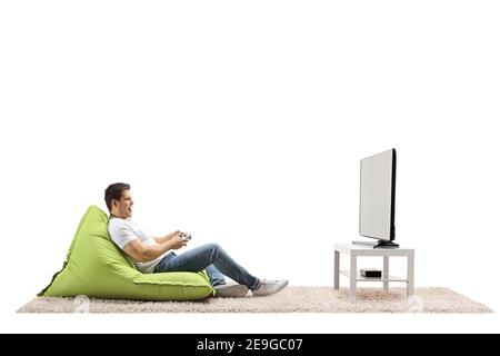 Young man sitting on a green bean bag and playing video games with a joystick at home in a living room Stock Photo