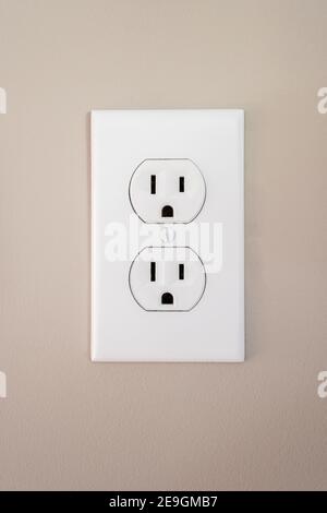A 115 amp white wall outlet with a face plate Stock Photo