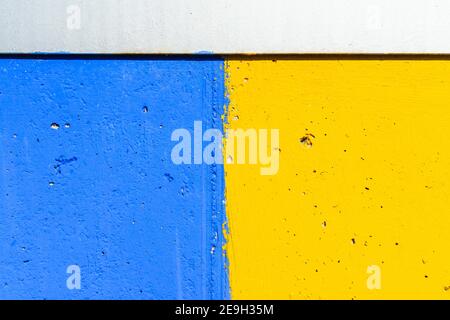 Closeup shot of a weathered wall painted with yellow and bl Stock Photo