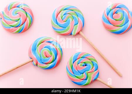 Colorful lollipops swirls on sticks. Striped spiral multicolored candy on pink background, top view Stock Photo