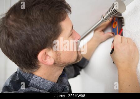 handyman services - worker installing window curtain rod Stock Photo
