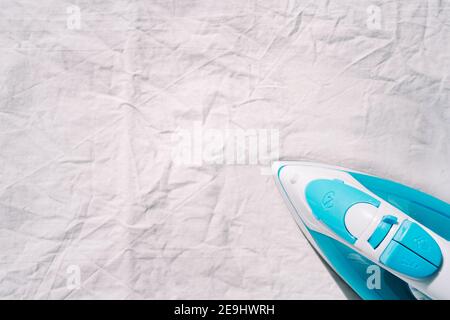 Blue iron on white crumpled fabric. Copy space Stock Photo