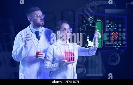Young scientists with samples using virtual screen on dark background Stock Photo