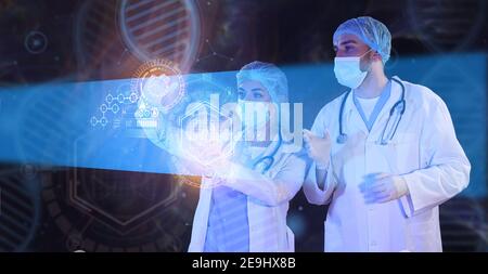 Young scientists using virtual screen on dark background Stock Photo