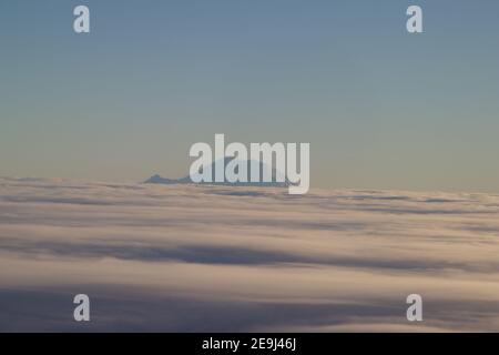 Mount Rainier emerging from the clouds, viewed from a plane, Washington, USA Stock Photo