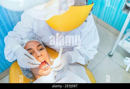 Cute woman sits in dentist chair while dentist examine her teeths. Selective focus. Stock Photo