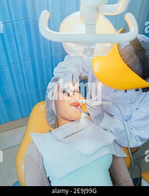 Cute woman sits in dentist chair while dentist examine her teeths. Selective focus. Stock Photo