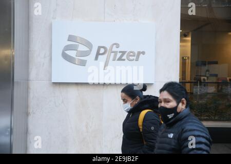 New York City, NY USA People wearing masks pass by Pfizer World Headquarters on 42nd Street in Manhattan Stock Photo