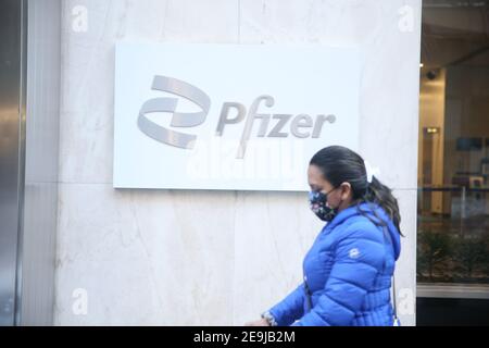 New York City, NY USA Woman walking past Pfizer World Headquarters on 42nd Street in Manhattan Stock Photo