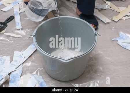 Mixing white plaster in a bucket with a stirrer. Close-up. Stock Photo