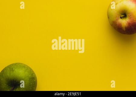 Green apple and yellow-red apple on a yellow background Stock Photo