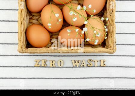Zero waste concept. No plastic concept. Minimal style. Beige water hyacinth box with brown chicken eggs on textile background. Zero vaste wooden text. Stock Photo