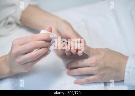 Close up picture of nail artists hands in gloves doing nail polishing Stock Photo