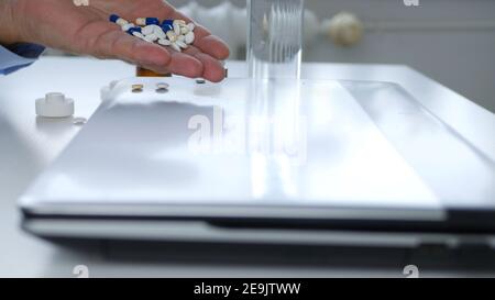 Image with a Sick Person Taking Medicaments and Working on Laptop Stock Photo