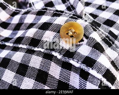 Wrinkled material plaid. Black and white checkered shirt fabric background. Button on fabric Stock Photo