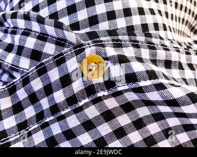 Wrinkled material plaid. Black and white checkered shirt fabric background. Button on fabric Stock Photo