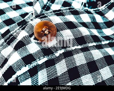 Wrinkled material plaid. Black and white checkered shirt fabric background. Button on fabric Stock Photo