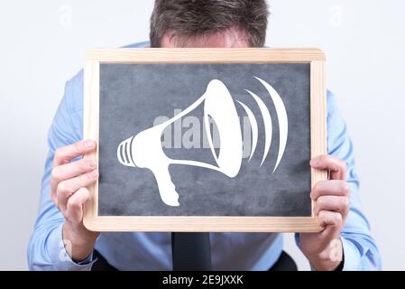 Businessman holding a blackboard with the symbol of a megaphone Stock Photo