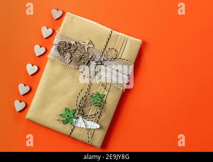 Book wrapped in craft paper with wooden decorations. Zero waste, eco friendly packaging gift. Stock Photo