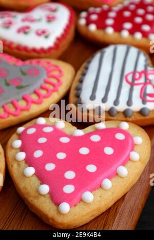 Fresh baked assorted lovely patterned heart shaped cookies on wooden breadboard Stock Photo