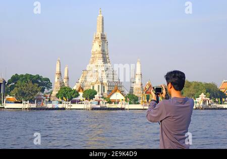 Man Taking Photos of the Temple of Dawn or Wat Arun, the Iconic Landmark Located on Chao Phraya River Bank, Bangkok, Thailand Stock Photo