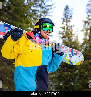 Portrait of Young Snowboarder with the Snowboard in the Winter Forest. Snowboarding and Winter Sports Stock Photo