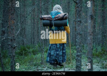KARELIA, RUSSIA - JUNE 6 2020: Girl with a backpack stands in a pine forest Stock Photo