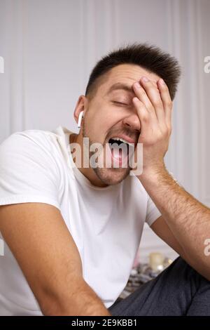 man laughs. portrait of handsome young man in earphones is talking to somebody on video call. Stock Photo