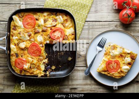 A freshly made Goat Cheese Frittata. The full Frittata is shown in the cooking pan with a slice onesie plate. An egg based healthy eating option Stock Photo
