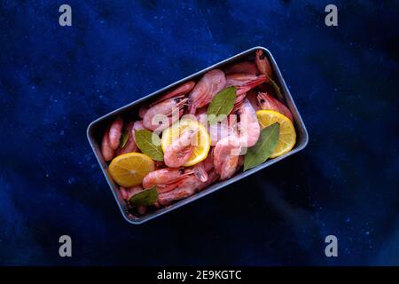 Raw shrimp prawns with ice and lemon on blue background, top view. seafood. with copy space Stock Photo