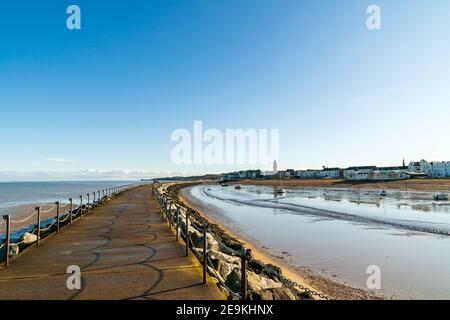 The harbour jetty at Herne Bay in Kent. View from the end of the pier looking along the sea and harbour as the jetty sweeps gently around to the coastal town on a winter's day with a blue sky. Low tide. Stock Photo