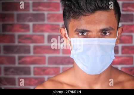 A young man with protective mask against a wall  Stock Photo