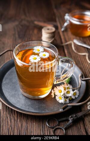 Herbal medicine for respiratory health, a cup of daisy tea with honey on rustic wooden background Stock Photo