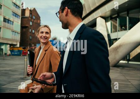Mixed race colleagues smiling while walking to offices chatting about upcoming projects Stock Photo