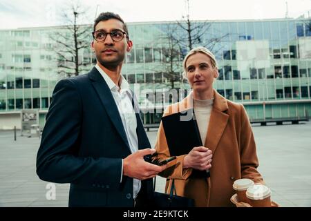Focused colleagues chatting over coffee before work starts Stock Photo