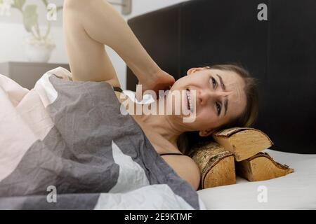 bad pillow and sleep quality concept. woman sleeping on stack of firewood and having neck pain Stock Photo