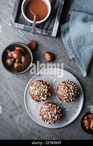 Sweet chestnut cups filled with soft curd cheese, chestnut puree and ground almonds, topped with chocolate frosting and chopped nuts on stone backgrou Stock Photo